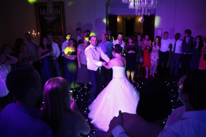 A bride and groom during their first dance on a black starlit dance floor at Buxted Park Hotel