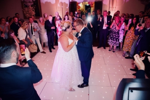 A bride and groom during their first dance at Buxted Park Hotel on a white starlit dance floor