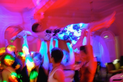 A woman being raised into the air by her friends at a party