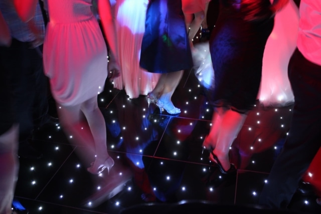 People dancing on a black starlit dance floor